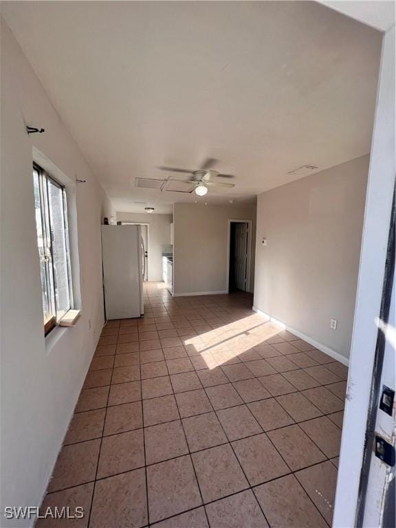 spare room with light tile patterned flooring, a ceiling fan, and baseboards