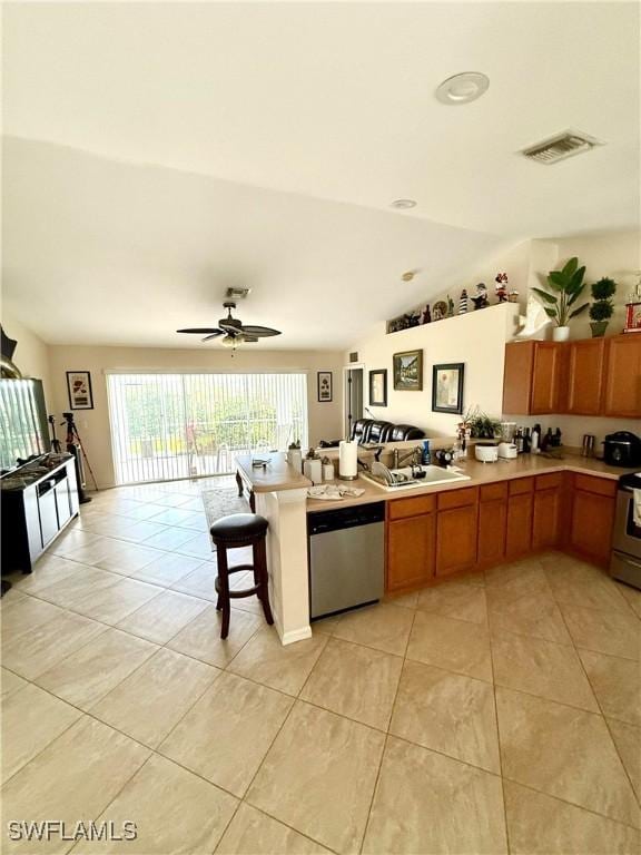 kitchen featuring visible vents, open floor plan, light countertops, dishwasher, and brown cabinetry