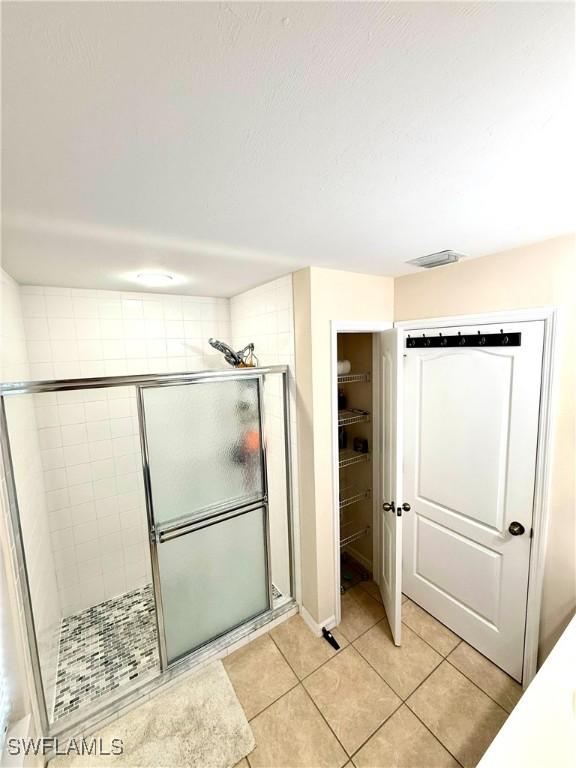 full bathroom with a stall shower, visible vents, a walk in closet, and tile patterned floors