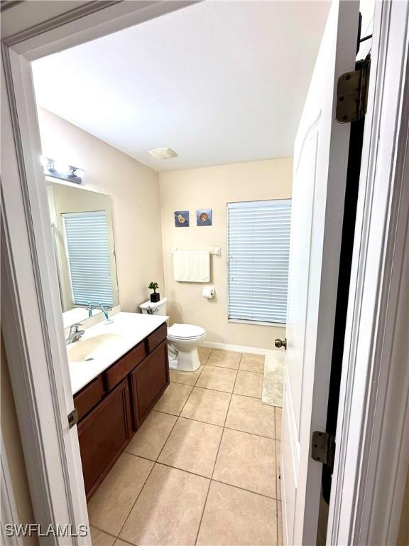 bathroom with toilet, baseboards, vanity, and tile patterned floors