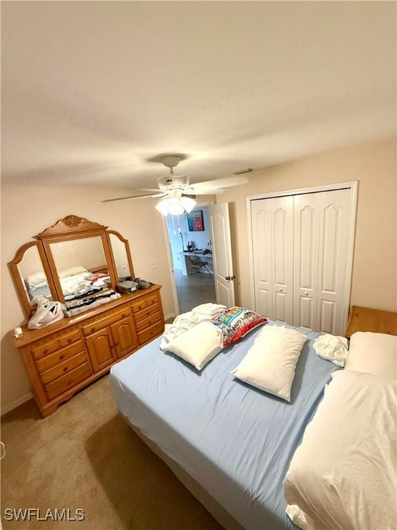 bedroom featuring light carpet, ceiling fan, and a closet