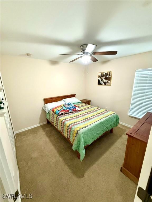 carpeted bedroom featuring a ceiling fan and baseboards