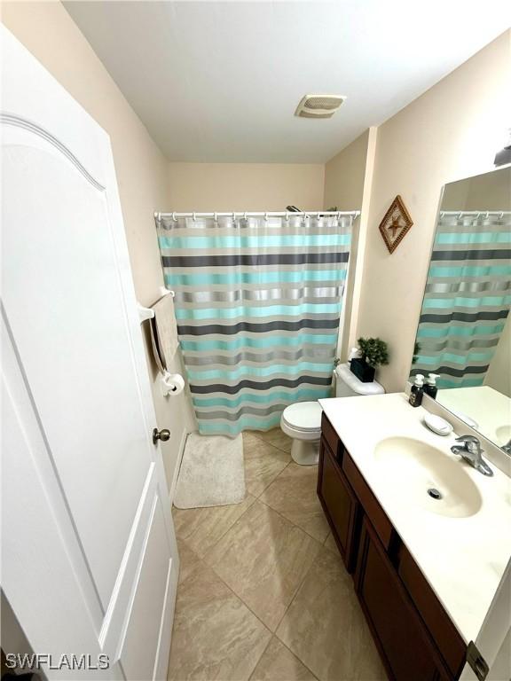 bathroom with toilet, visible vents, a shower with shower curtain, and vanity