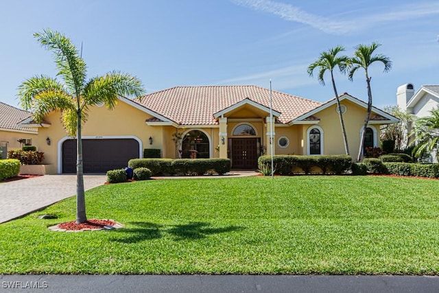 mediterranean / spanish-style house featuring decorative driveway, stucco siding, a front yard, a garage, and a tiled roof