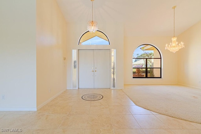 tiled entrance foyer featuring a chandelier, high vaulted ceiling, carpet, and baseboards