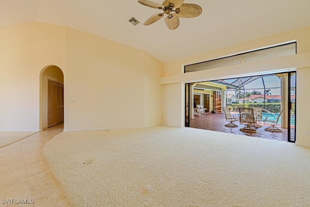 carpeted spare room featuring ceiling fan, arched walkways, tile patterned flooring, visible vents, and a sunroom