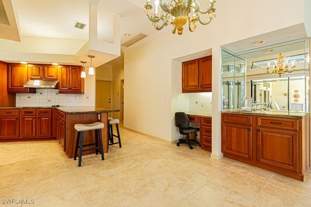 kitchen with built in desk, backsplash, visible vents, and under cabinet range hood