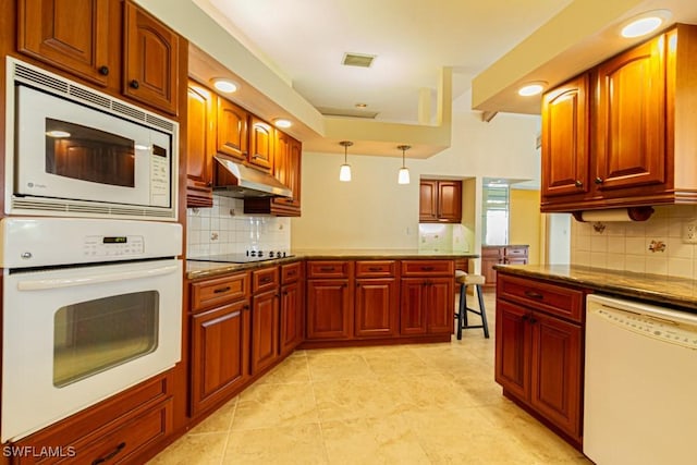 kitchen featuring white appliances, tasteful backsplash, visible vents, hanging light fixtures, and under cabinet range hood