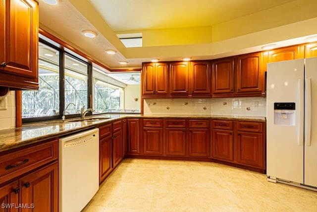 kitchen with stone countertops, white appliances, a sink, and decorative backsplash