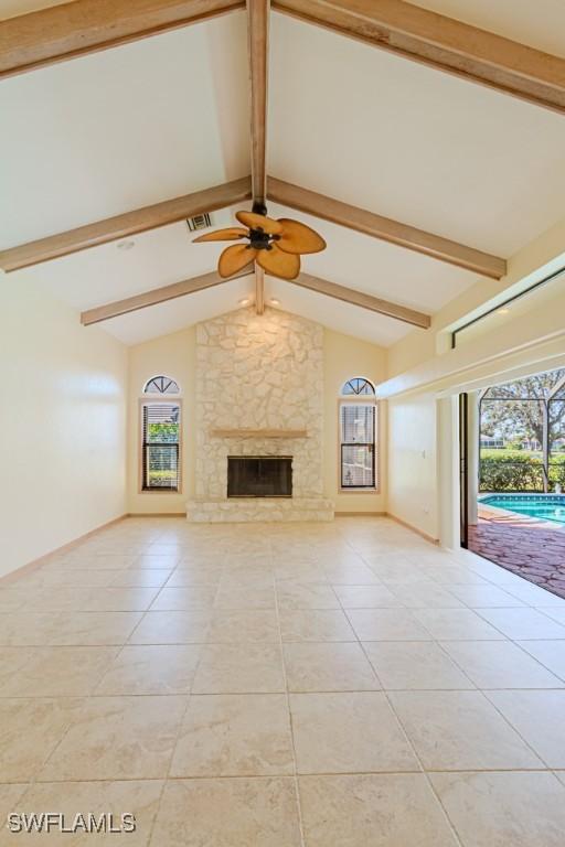 unfurnished living room with vaulted ceiling with beams, light tile patterned floors, a fireplace, and a wealth of natural light