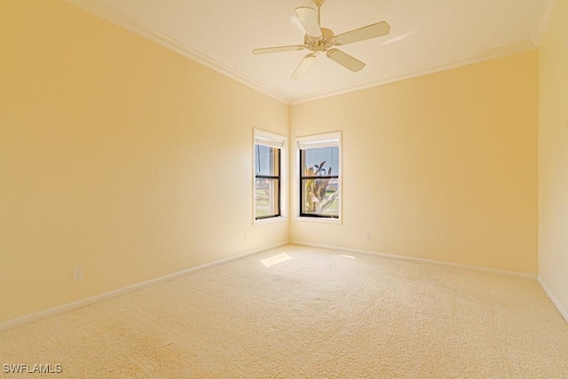 carpeted empty room featuring a ceiling fan, baseboards, and crown molding