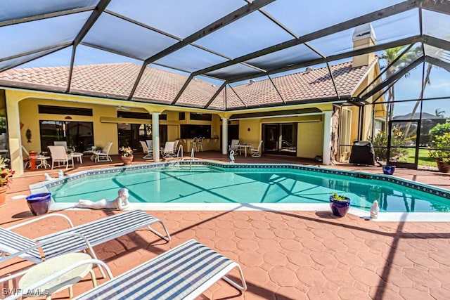 outdoor pool featuring glass enclosure and a patio area