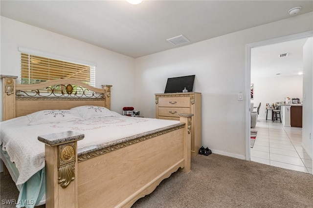 bedroom featuring light carpet, light tile patterned floors, visible vents, and baseboards