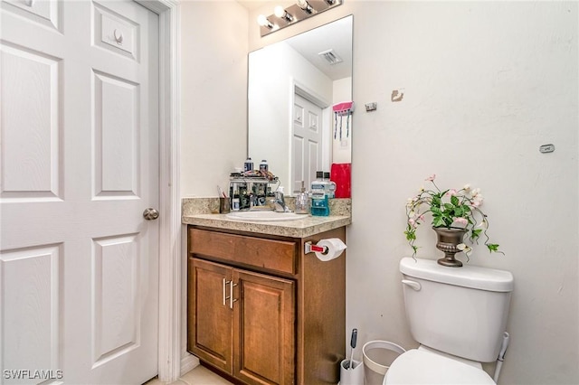 bathroom with toilet, vanity, and visible vents