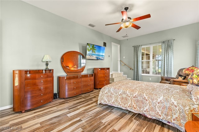 bedroom with wood finished floors, visible vents, and ceiling fan