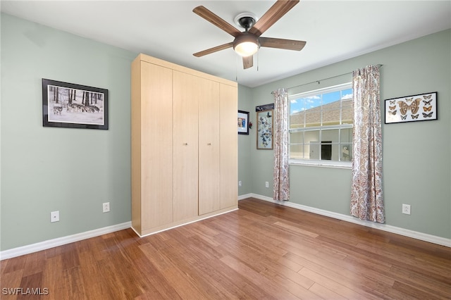 unfurnished bedroom featuring a closet, a ceiling fan, baseboards, and wood finished floors