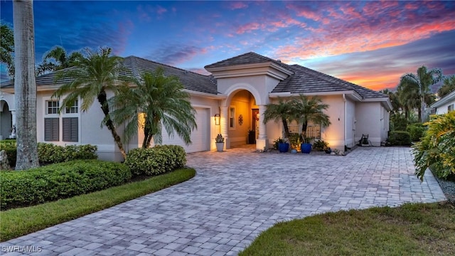 view of front of home featuring a garage, decorative driveway, and stucco siding