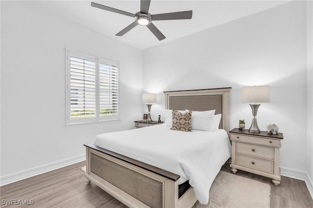 bedroom featuring ceiling fan, light wood-style flooring, and baseboards