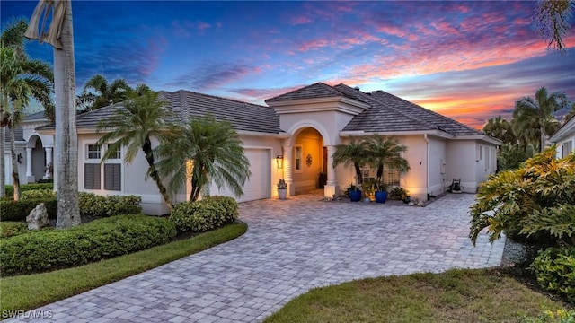 mediterranean / spanish-style home with a garage, decorative driveway, and stucco siding