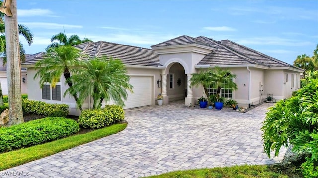 view of front of house with decorative driveway, an attached garage, and stucco siding