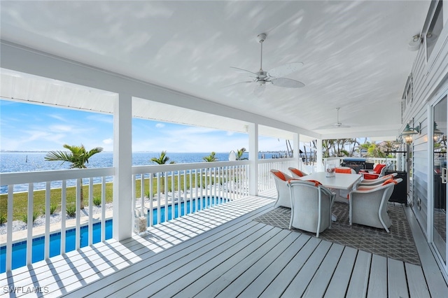 deck featuring a water view, ceiling fan, a fenced in pool, and outdoor dining space