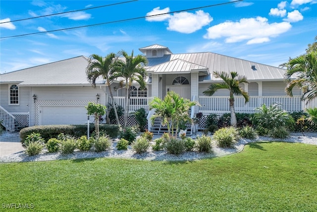 view of front facade with driveway, metal roof, an attached garage, a front lawn, and a porch