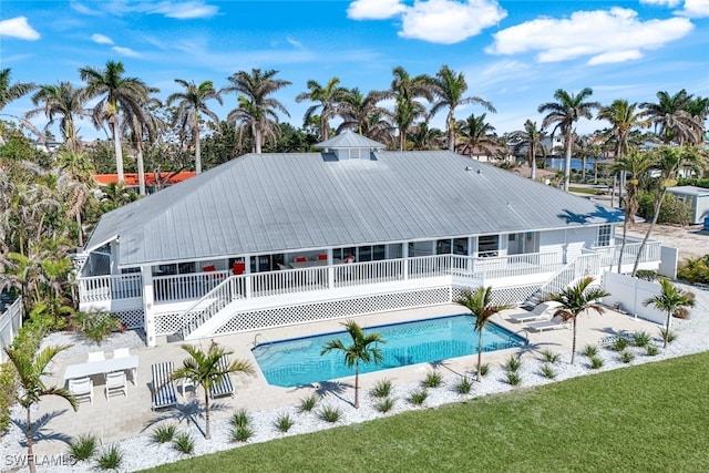 back of house featuring stairway, a patio area, metal roof, fence, and an outdoor pool