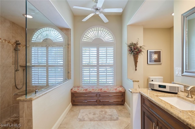 bathroom featuring a ceiling fan, vanity, baseboards, and a walk in shower