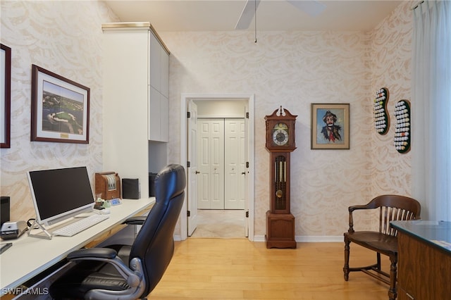 office space with light wood-type flooring, wallpapered walls, ceiling fan, and baseboards