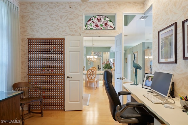 office space with wallpapered walls, light wood-style flooring, visible vents, and a notable chandelier