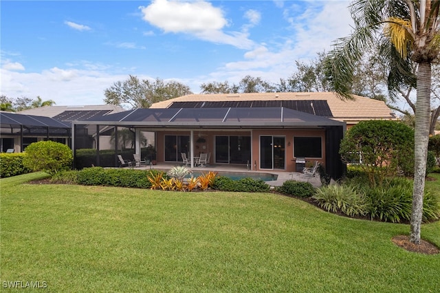 rear view of house with a lawn, a patio area, a lanai, and roof mounted solar panels