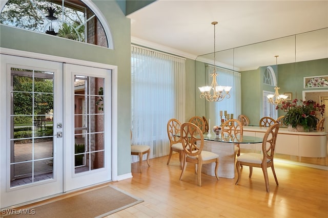 dining area featuring french doors, plenty of natural light, light wood finished floors, and an inviting chandelier