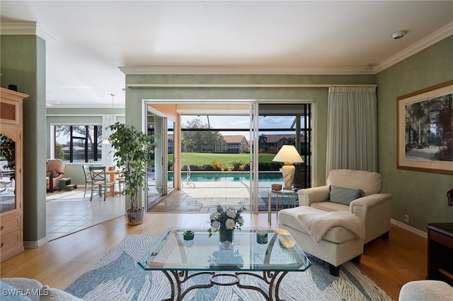 living area featuring light wood-style floors, ornamental molding, and baseboards