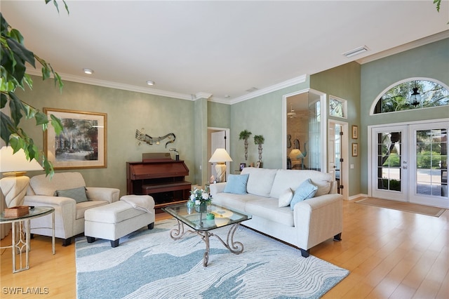 living area with visible vents, french doors, ornamental molding, and light wood-style flooring