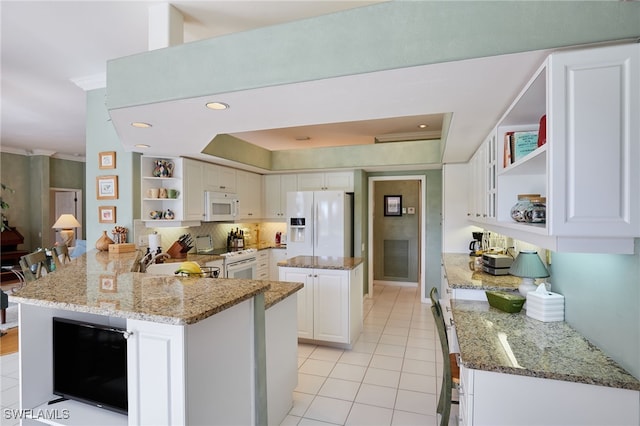 kitchen featuring white appliances, white cabinets, a peninsula, light stone countertops, and open shelves