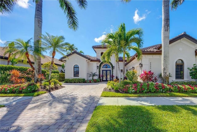 mediterranean / spanish home featuring stucco siding, a tiled roof, and french doors