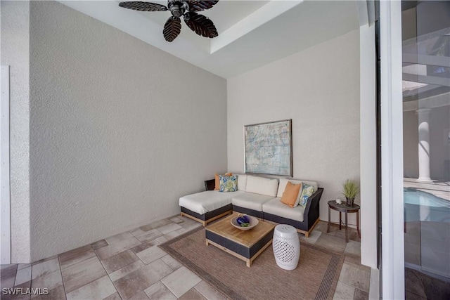 living room with a textured wall and ceiling fan