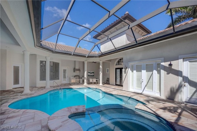 view of swimming pool featuring a patio area, a pool with connected hot tub, and glass enclosure