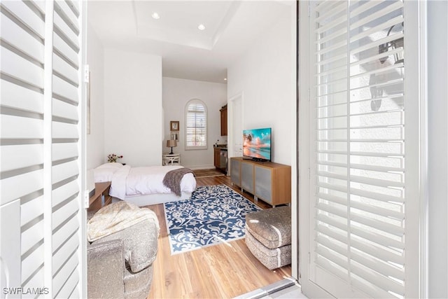 bedroom featuring recessed lighting, a raised ceiling, and wood finished floors