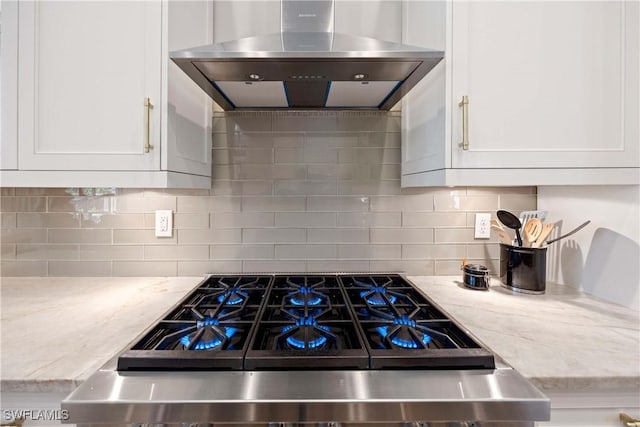 kitchen featuring white cabinets, wall chimney range hood, decorative backsplash, and stove