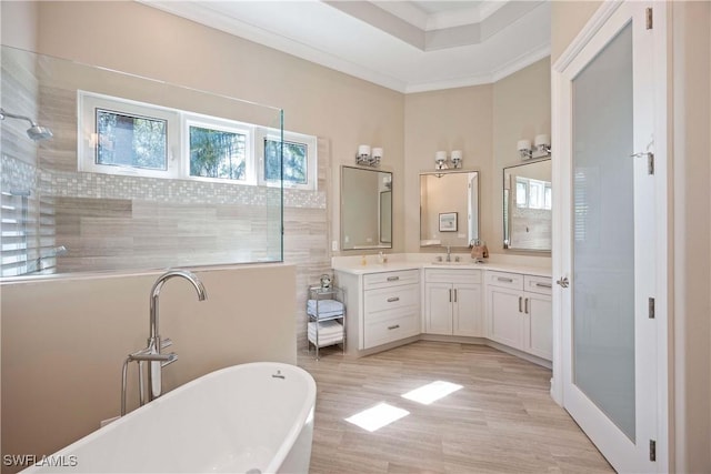 bathroom featuring ornamental molding, vanity, wood finished floors, a freestanding tub, and tiled shower