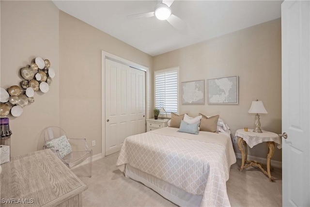 bedroom featuring a ceiling fan, baseboards, a closet, and light colored carpet