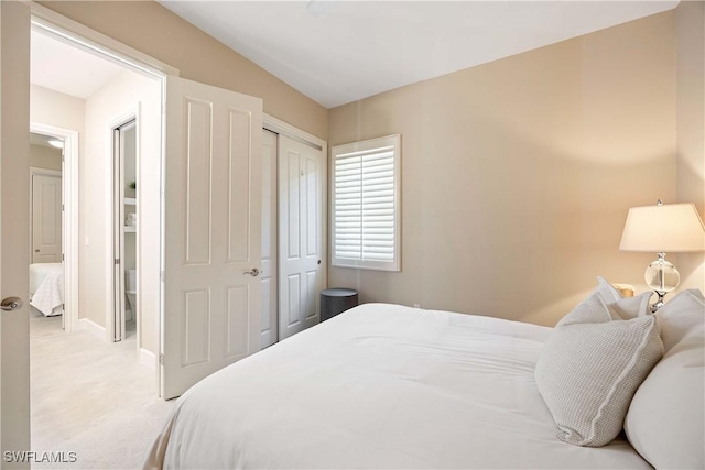 bedroom featuring baseboards, a closet, and light colored carpet