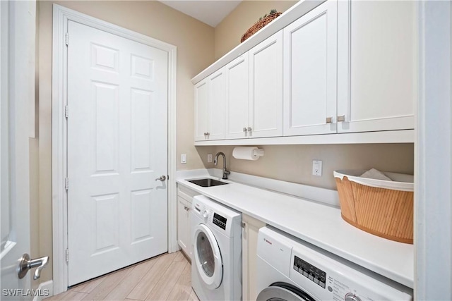 washroom featuring washing machine and clothes dryer, a sink, and cabinet space