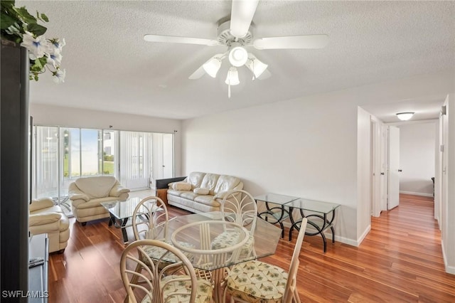 living room featuring ceiling fan, a textured ceiling, wood finished floors, and baseboards