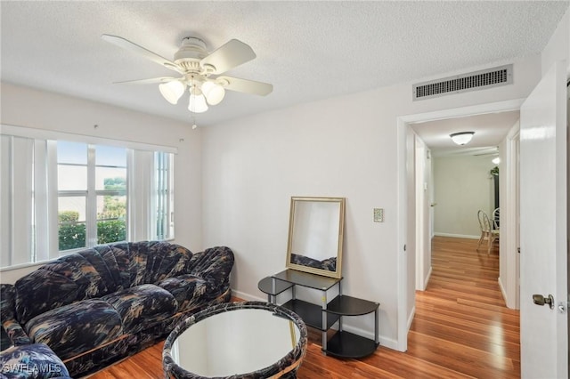 living area featuring visible vents, a textured ceiling, and wood finished floors