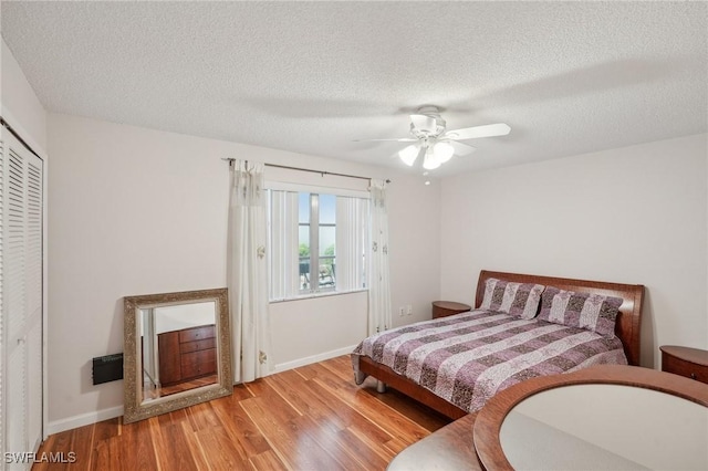 bedroom with ceiling fan, a textured ceiling, baseboards, and wood finished floors