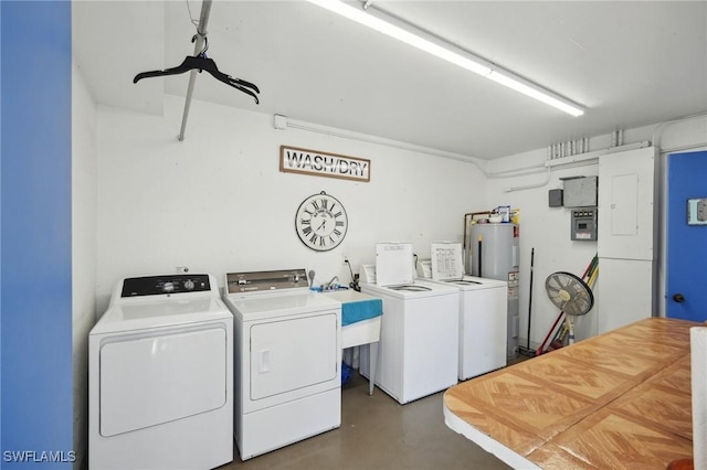 laundry area featuring washing machine and dryer, water heater, and a sink