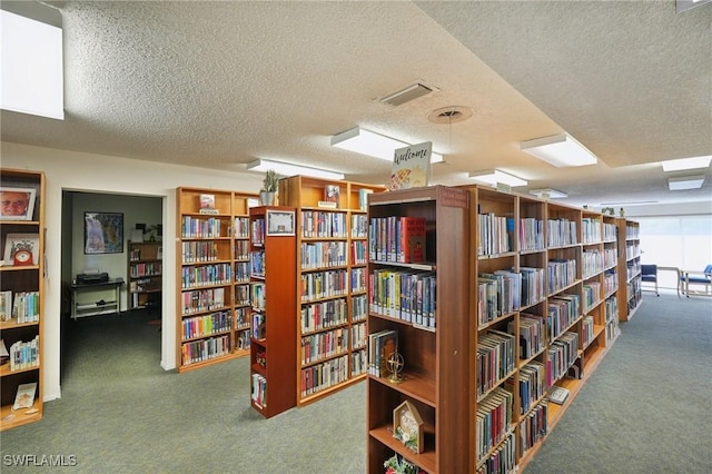 interior space with carpet, bookshelves, visible vents, and a textured ceiling