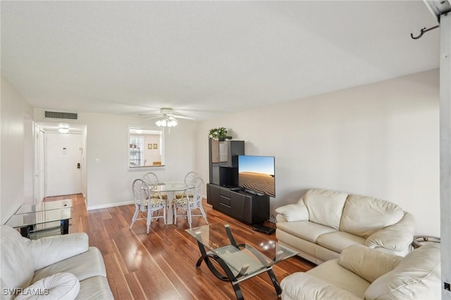 living area featuring ceiling fan, wood finished floors, visible vents, and baseboards